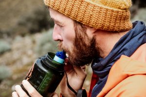 Comment prévenir le mal d'altitude à 2500m ? un homme boit de l'eau